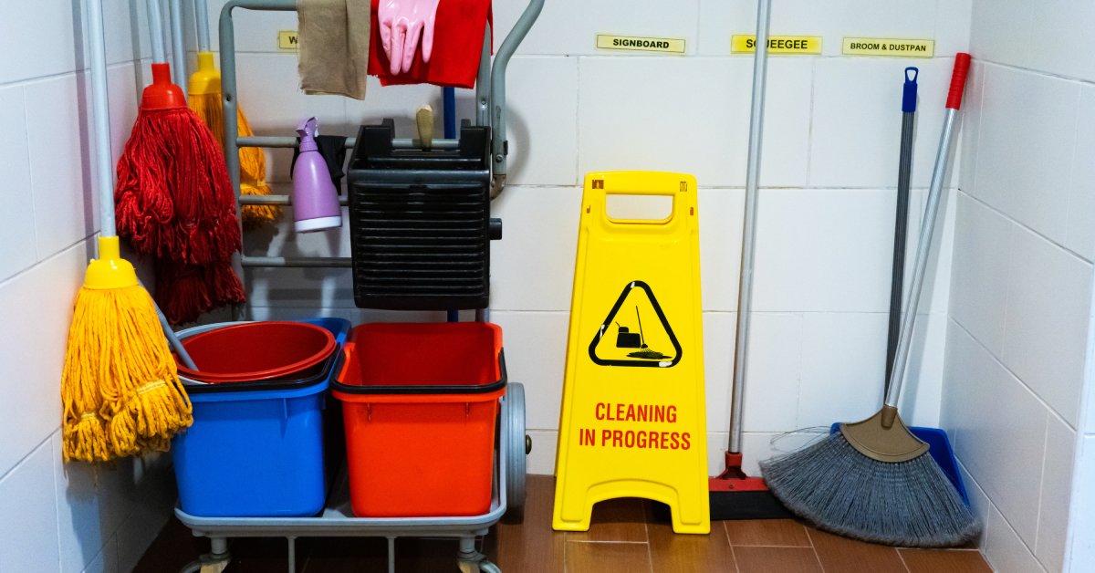 A janitorial cart fully stocked with various cleaning supplies, including mops, brooms, and spray bottles.
