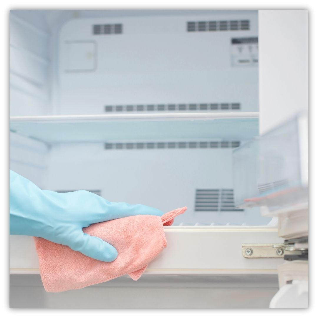 a person wiping down the inside of a fridge