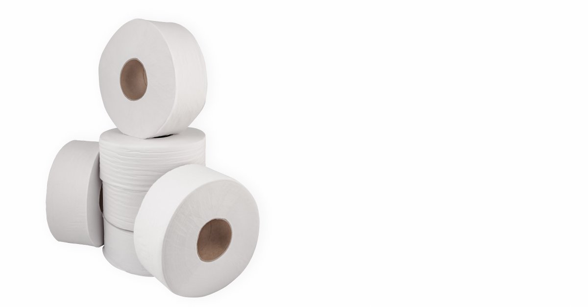 Three jumbo rolls of toilet tissue are stacked on top of each other, and three rolls are sitting upright.